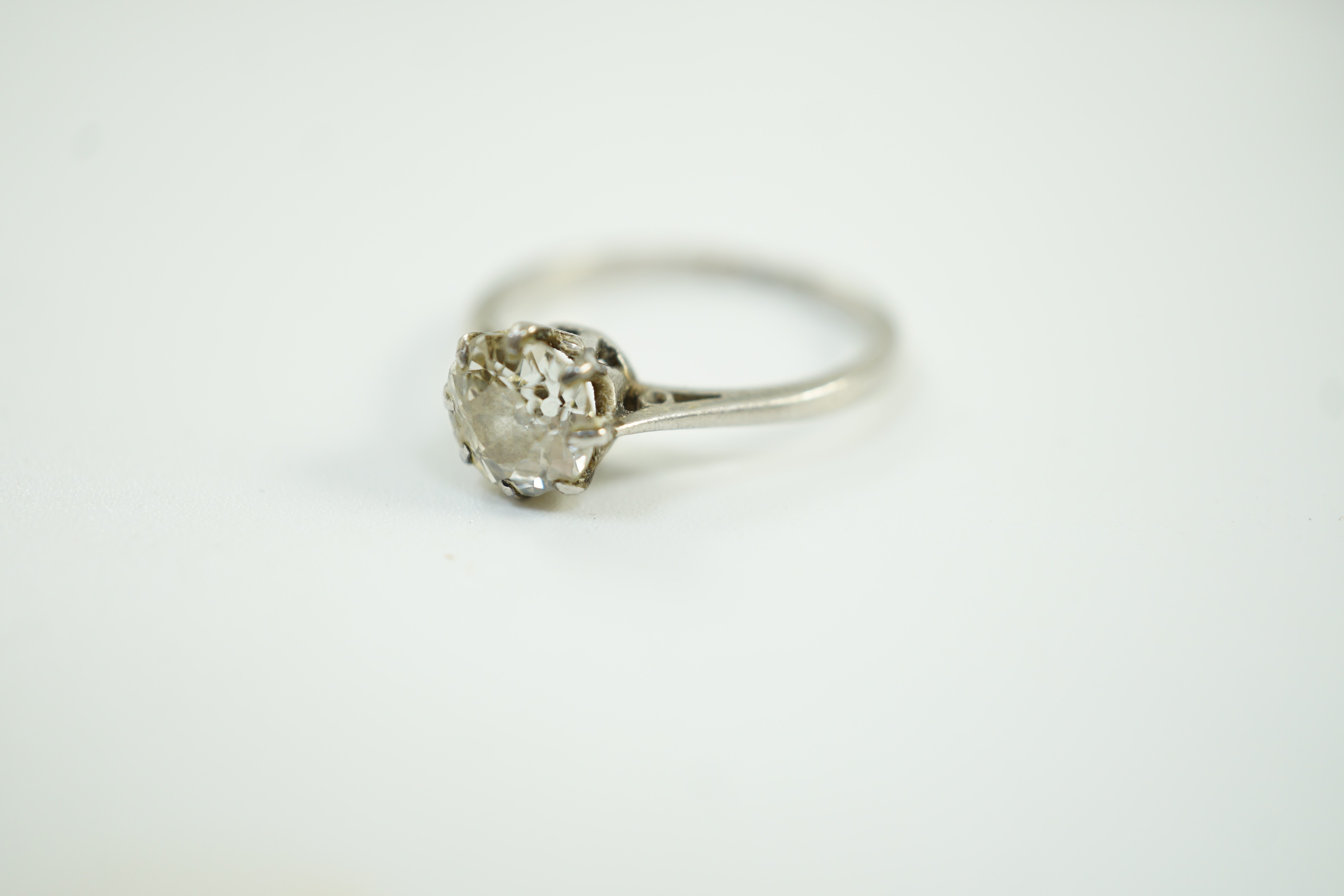 A white metal (stamped plat) and solitaire diamond ring, size J, gross weight 2.6 grams